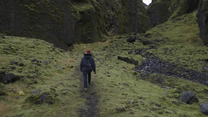 Woman walking up the green slopes in the mountain