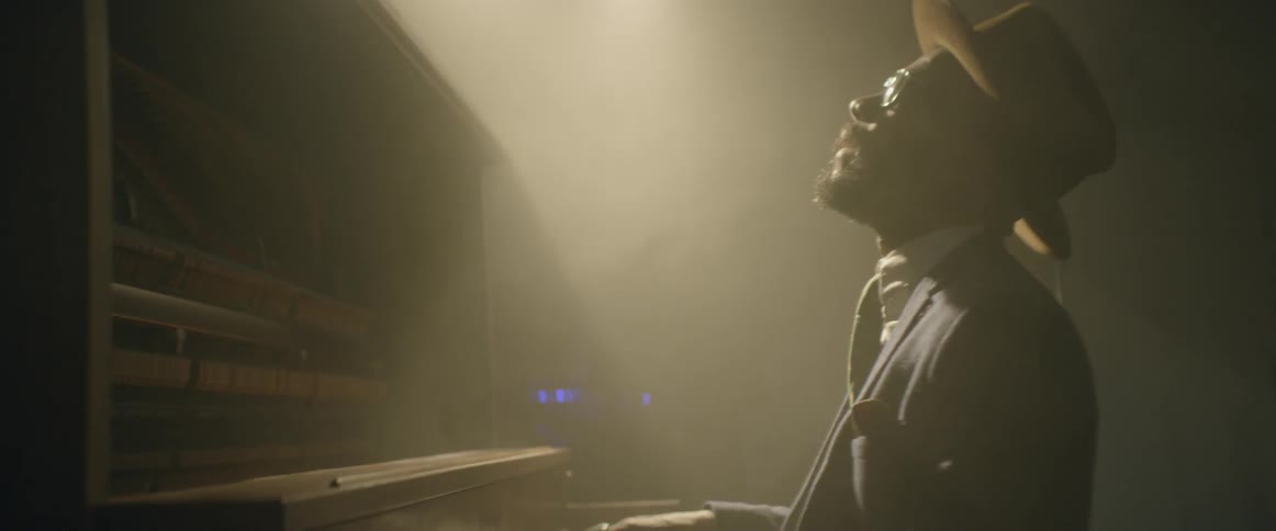 A man is playing a large piano under a spotlight
