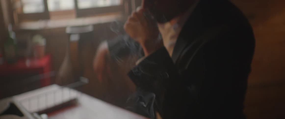 Smoke billows in front of a man sitting at a table