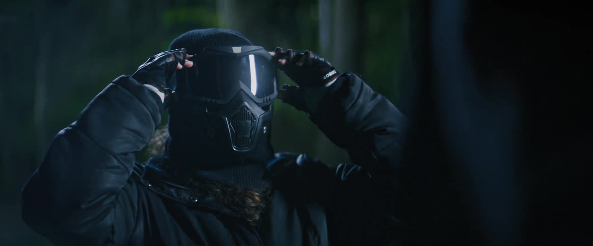 Person putting on a mask on their face in an outdoor setting at night
