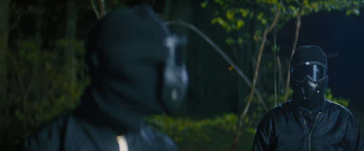 Two masked people in the forest at night