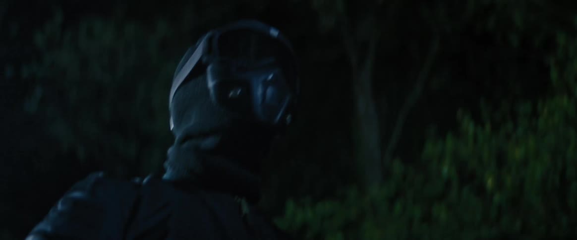A person wearing all black and a black mask is walking at night