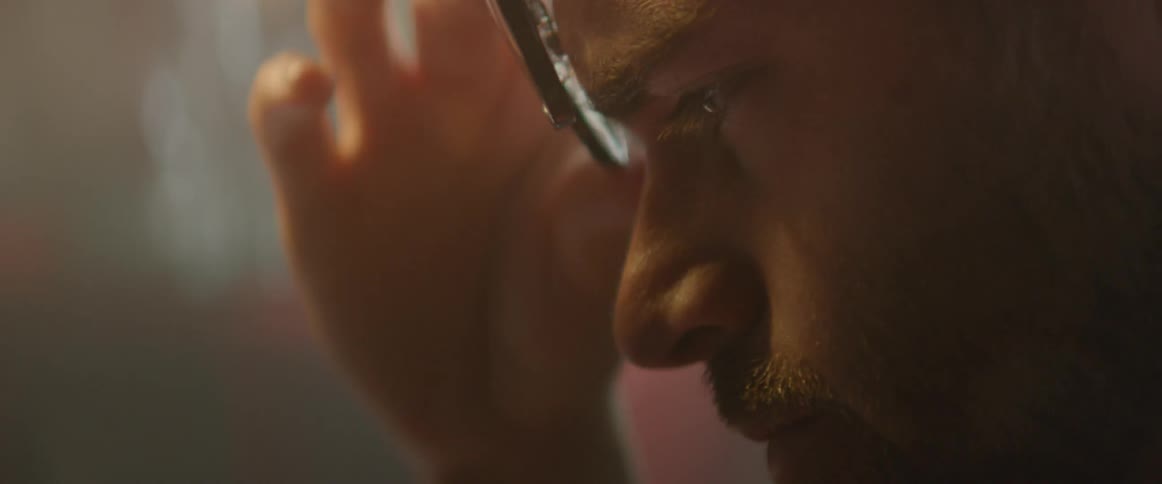 Man rubs eyes and then adjusts his glasses
