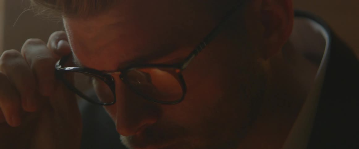 A man puts on glasses that reflect a typewriter below