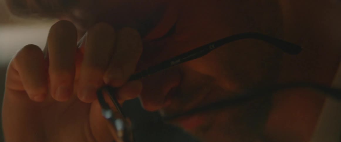 A man rubs his eyes while holding his glasses in his hand