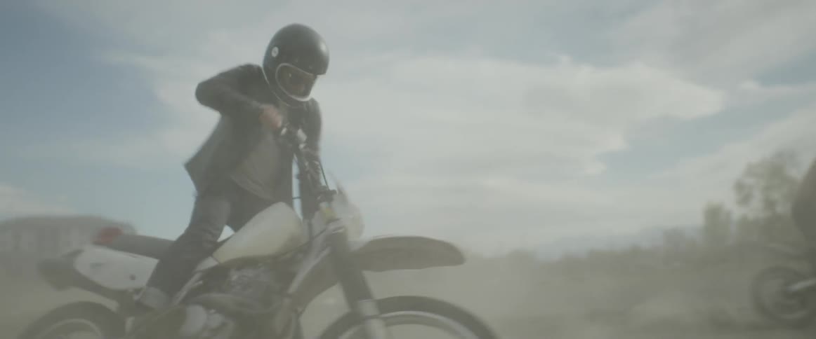 A motorcyclist kicks up dust and gravel as he rides his bike in circles