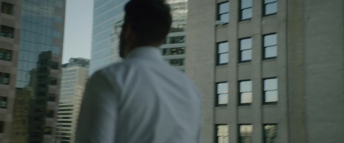 A man walks outside between tall city buildings