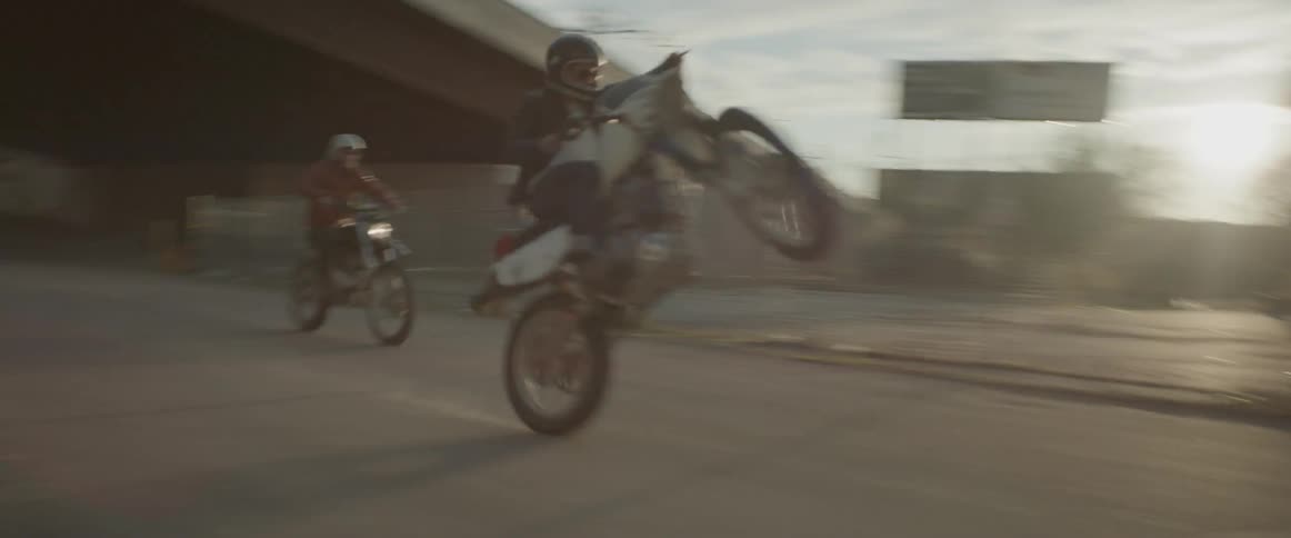 Two people on dirt bikes ride along road
