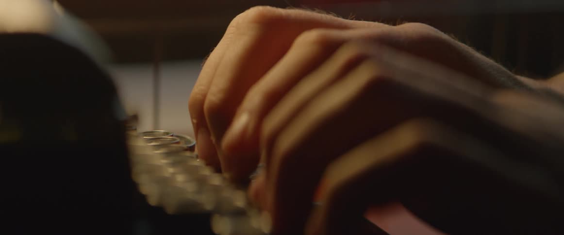 A person types on an old typewriter on a desktop