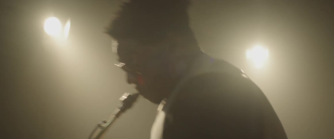 A man plays saxophone in a smoky room