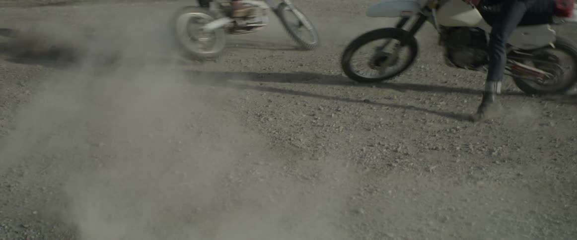 Men on motorcycles are spinning in circles kicking up dust