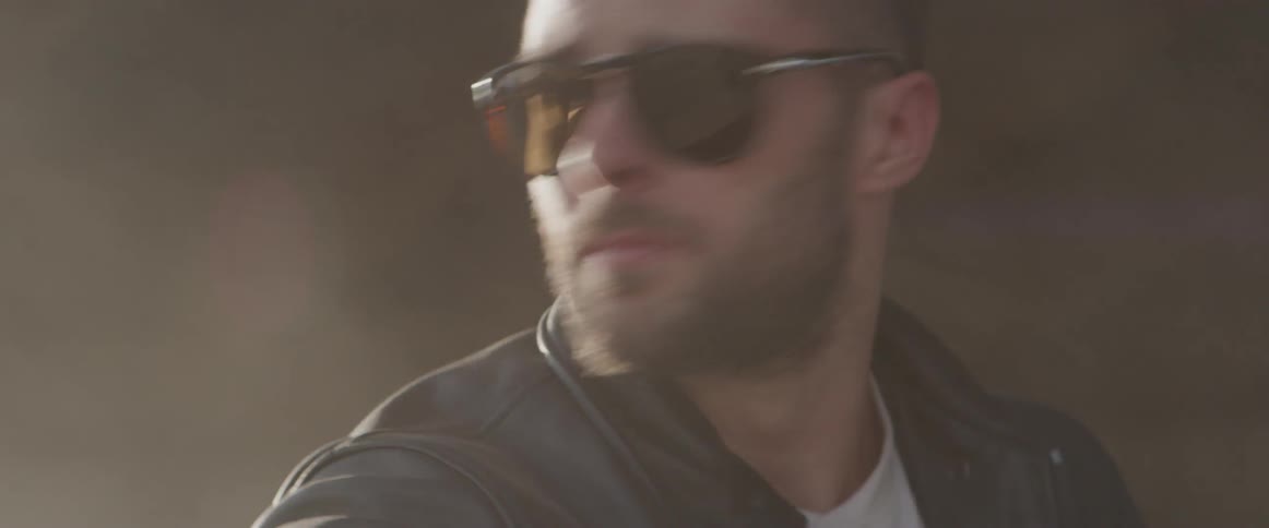 Bearded man takes off his motorcycle helmet and put on sunglasses
