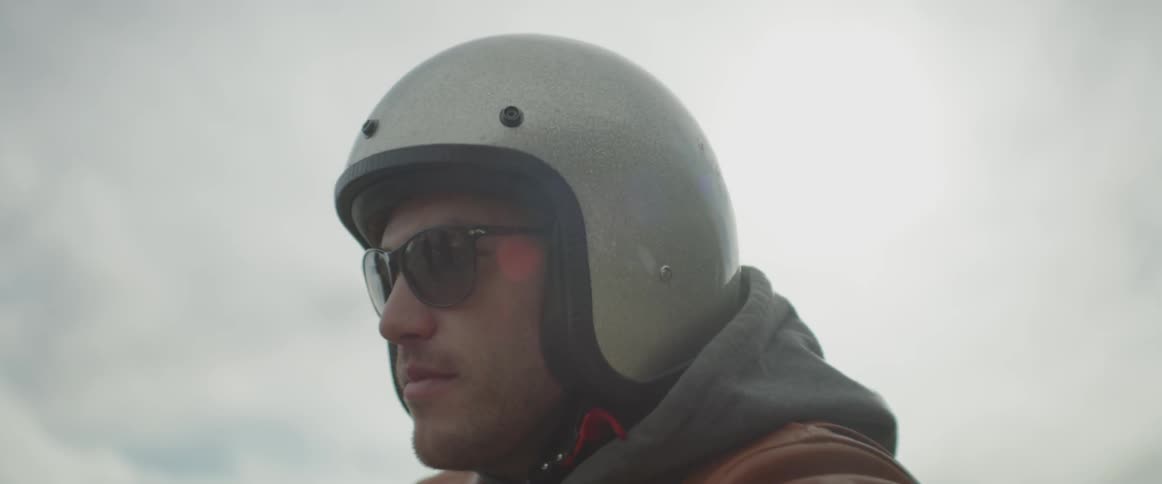 Man wearing sunglasses, helmet, hoodie and leather jacket
