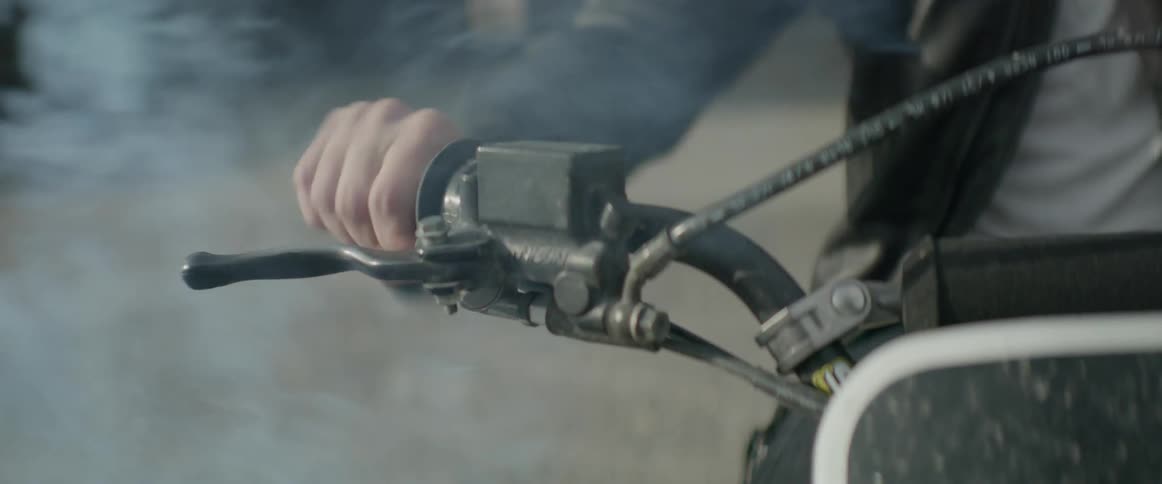 A person turns the handle on a motorcycle giving off smoke