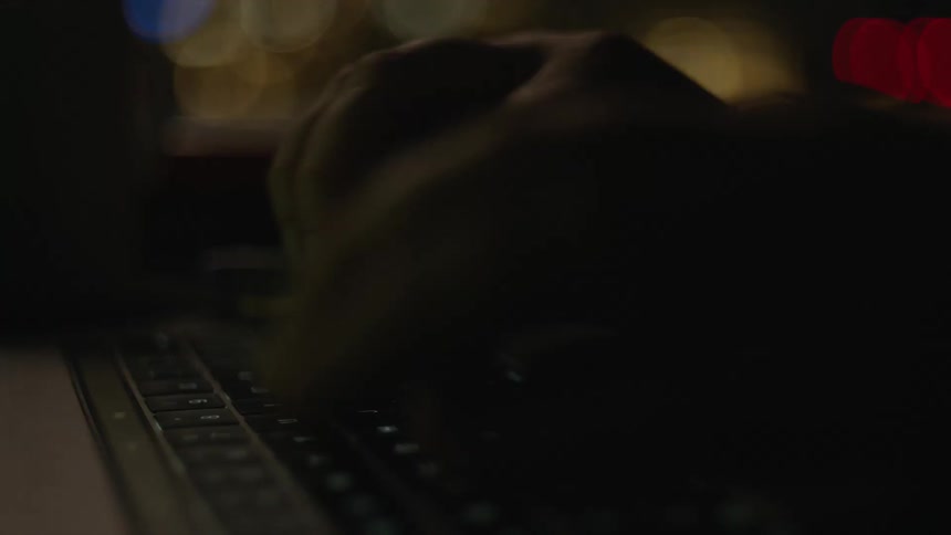 Close up of a person typing on a laptop keyboard at night