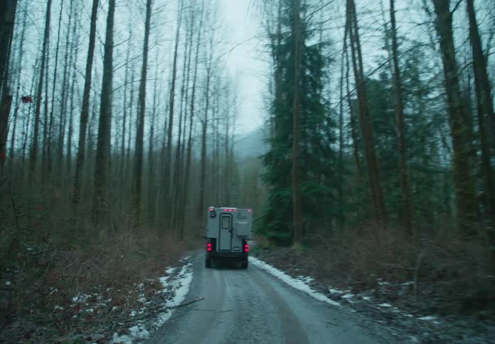 Truck on a dirt road in the middle of a forest on a cloudy winter day