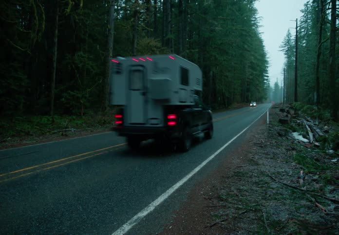 Vehicles traveling along a forest road during a blizzard
