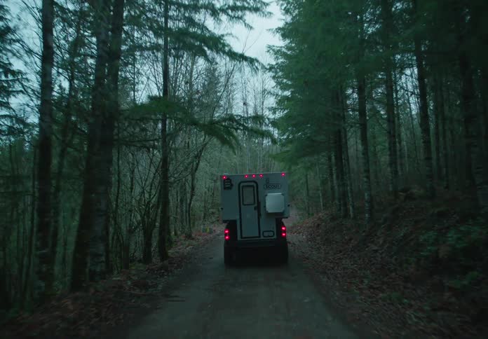 A trailer truck driving across a forest