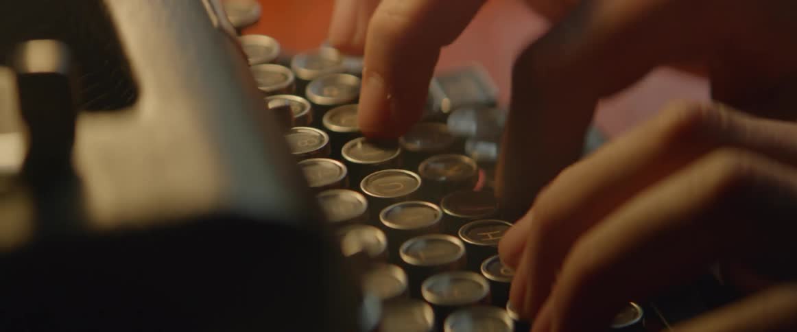 A man is pressing keys on a typewriter