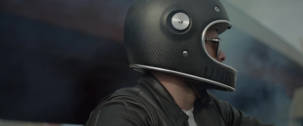Smoke billows around a motorcyclist wearing a helmet and leather jacket