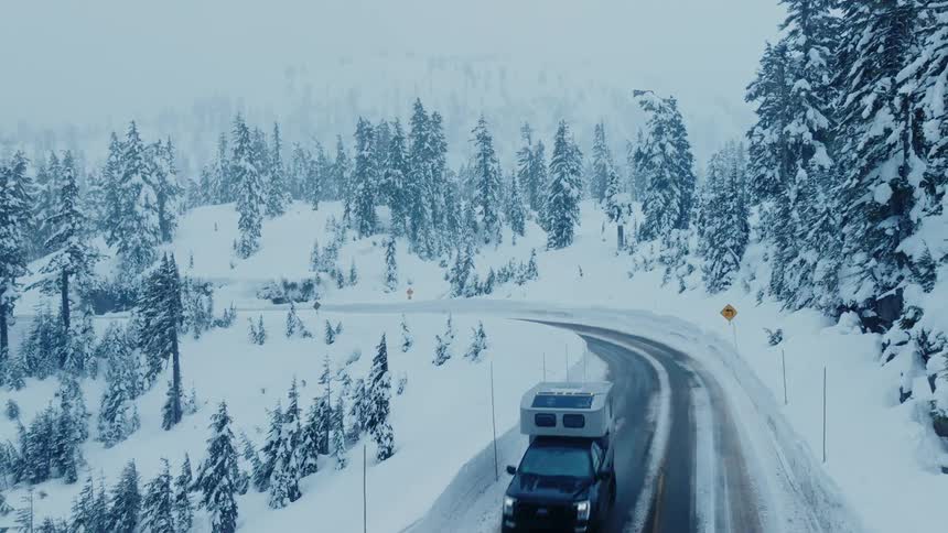 A vehicle drives down the snow filled road