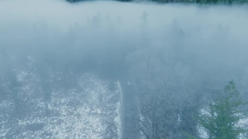 A car driving on a street in a snowy and foggy environment