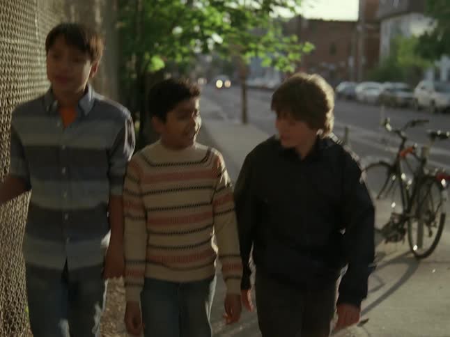Three little boys walking on the sidewalk in daylight