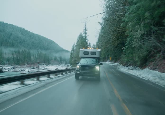 A truck is driving on the road by the river