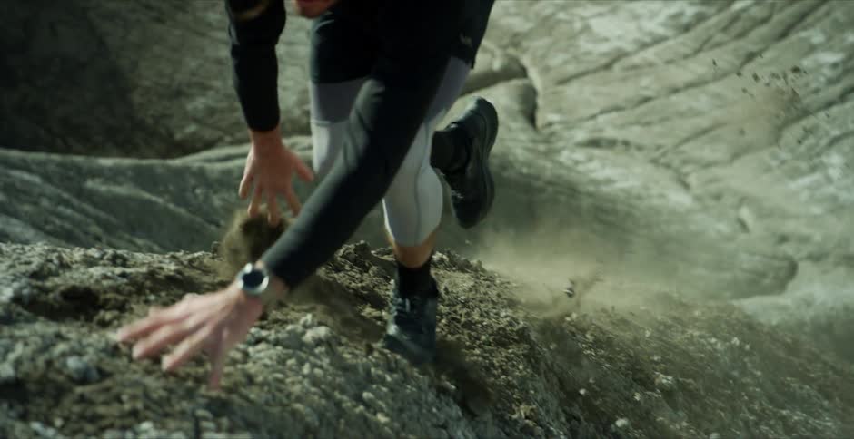 A man is running up a hill of sand and small stones