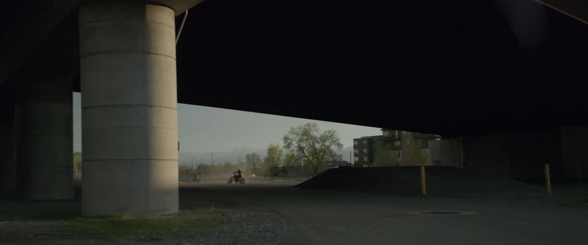 A motorcyclist turns his bike under a bridge