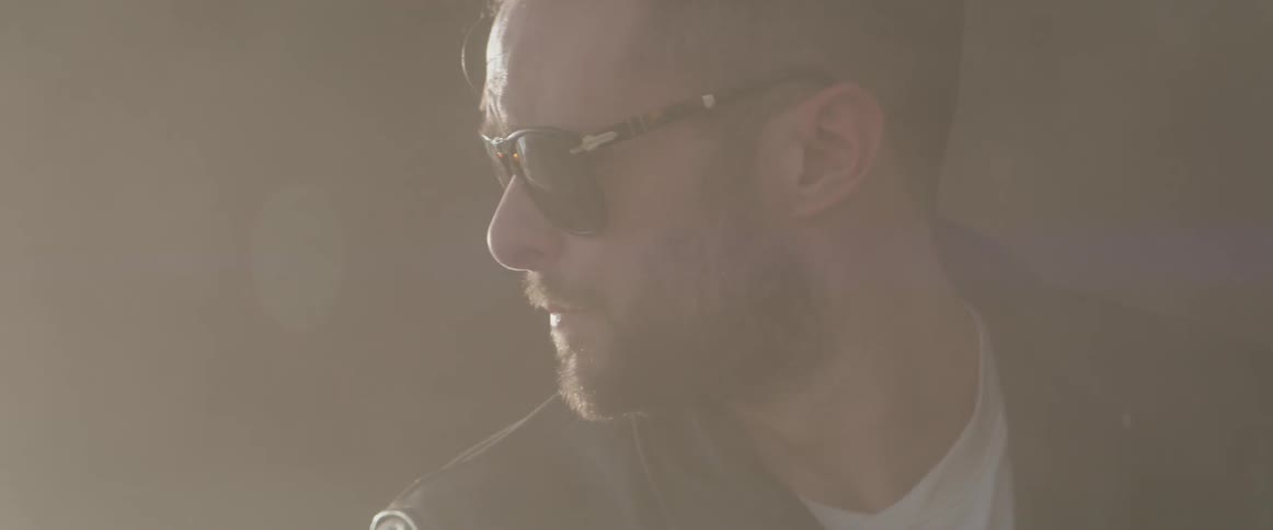A man takes off his motorcycle helmet and puts on sunglasses
