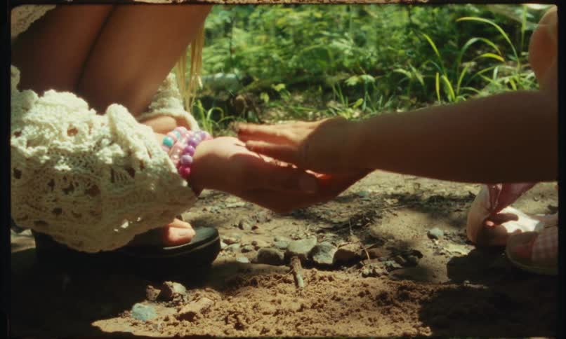 Two girls playing with dirt and pebbles in the forest