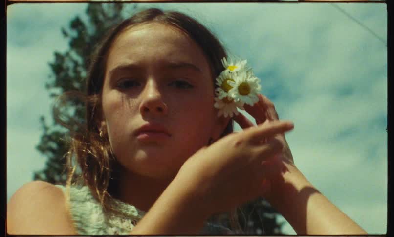 Teenager tries to put flowers behind her ear but they fall off