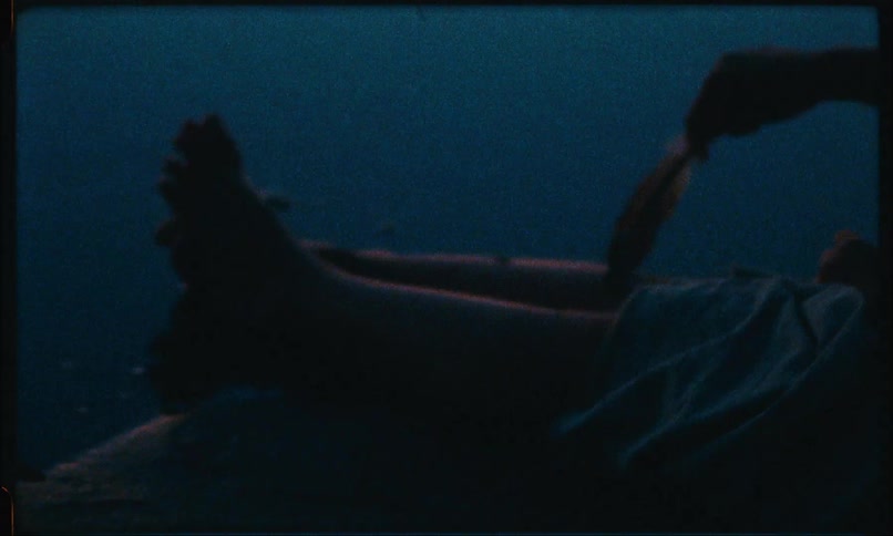 Closeup of a hand passing a feather over the legs of a person