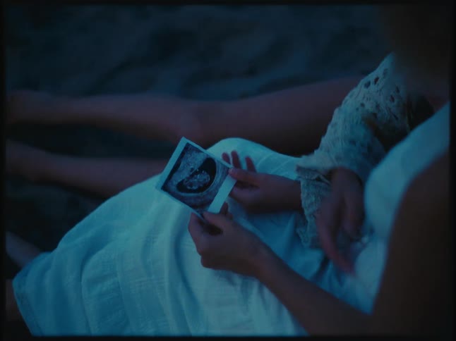A person holding a pregnancy ultrasound scan in their hands