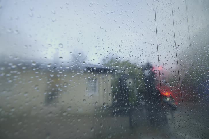 A car window with several drops of water and soft ambulance in the background