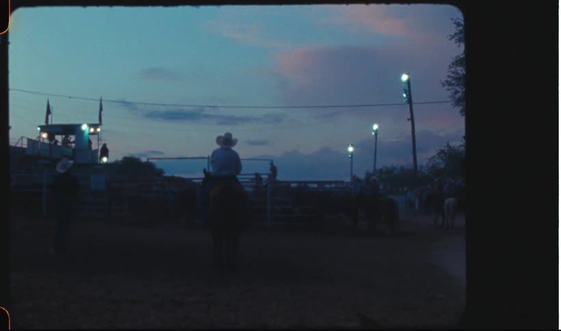 Cowboy riding a horse on a rodeo at sunset