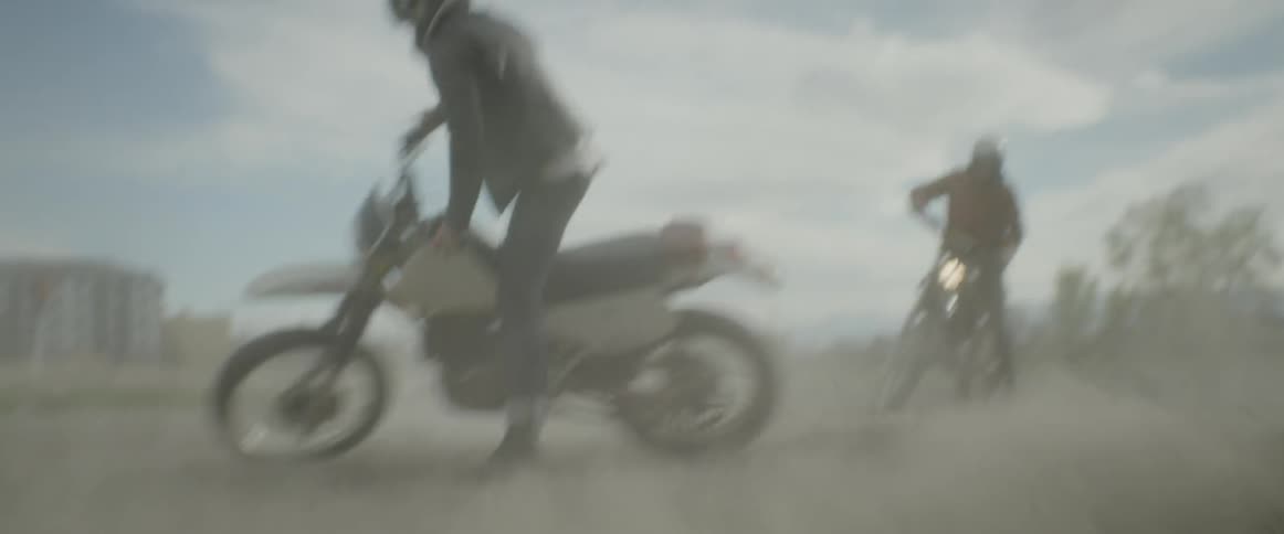 Two people spin their bikes and kick up dust