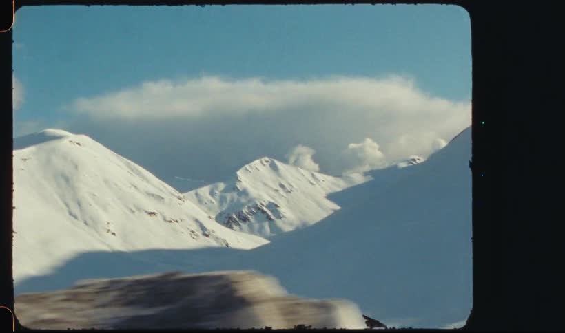 Vehicles including rv park near snow covered mountain range on a sunny winter day