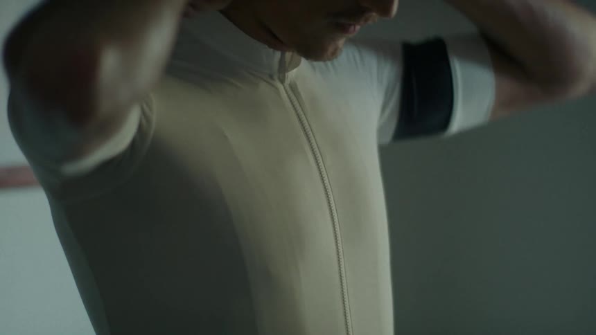 A man is zipping up his white shirt