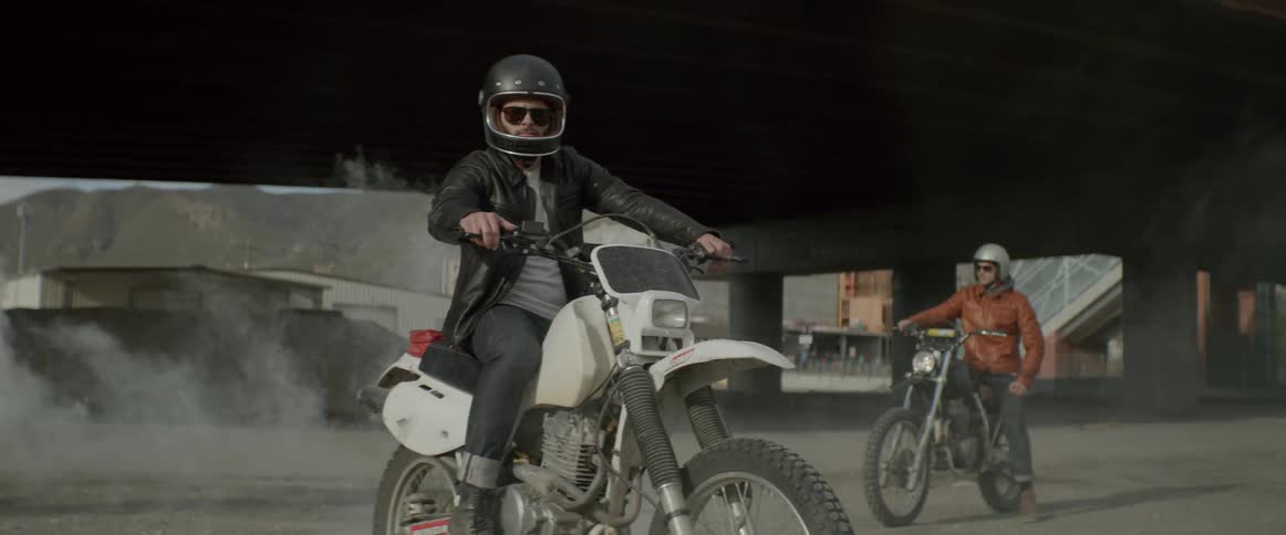 Two men sit still on their dirt bike