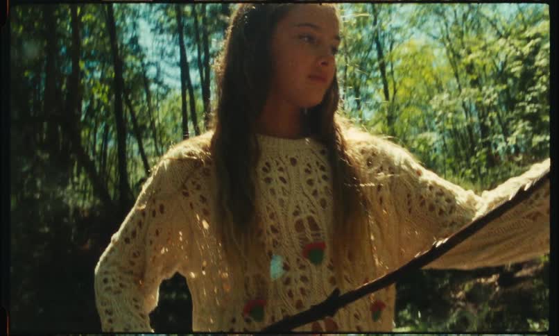 Young teenager holding a piece of wood in the middle of a forest in daylight