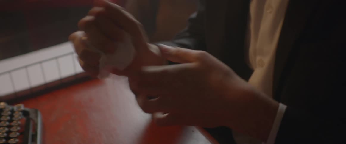A man crumbles up a piece of paper and throws it off of his desk