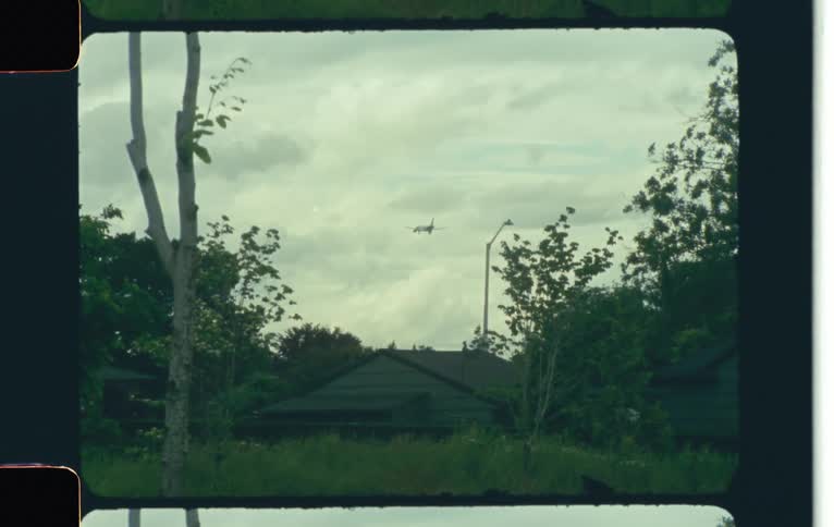 Airplane flying over a house caught on vintage film