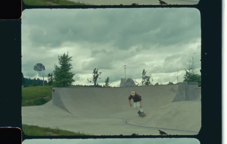 Man rides a skateboard in a park caught on vintage film