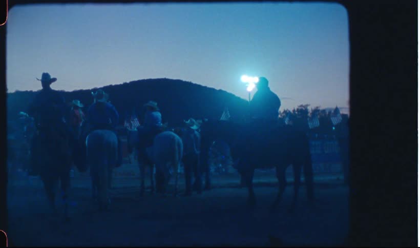 Several people are riding horses and it is dark and there is only one light on a post