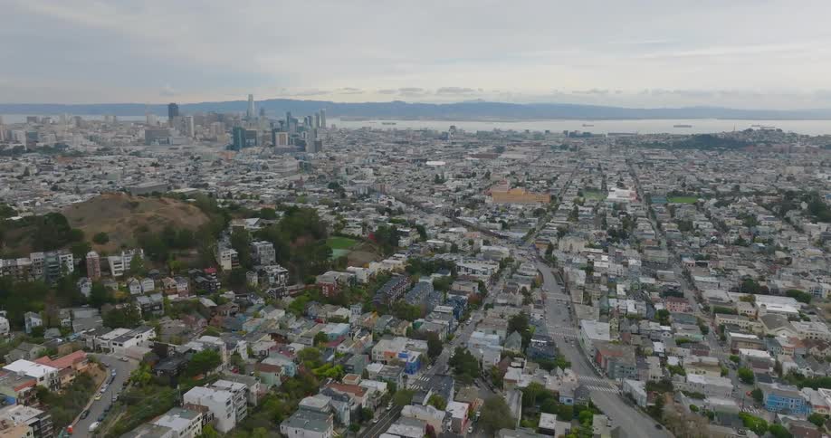 Wide road winds through residential neighborhood passing mountain on route to city downtown near the water front