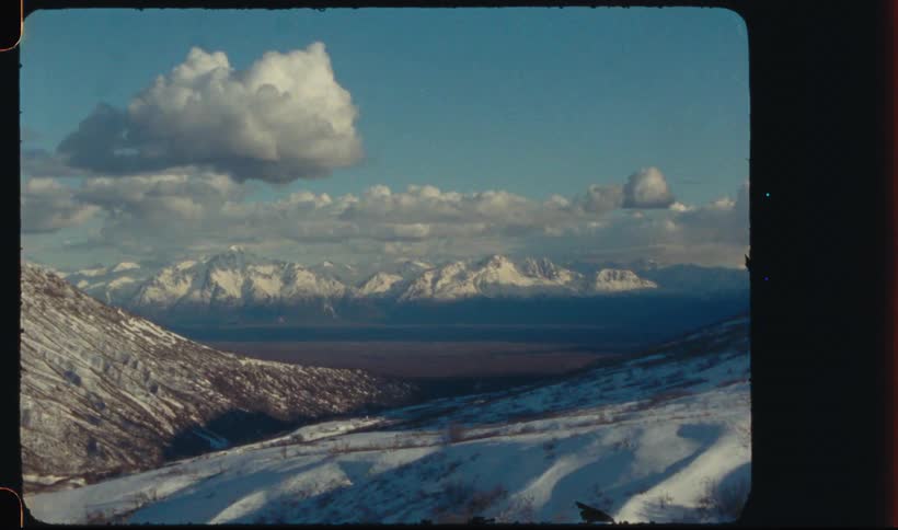 A landscape of mountains with snow on the horizon