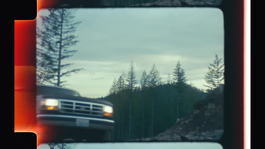 A pickup truck driving on a road in the forest at morning