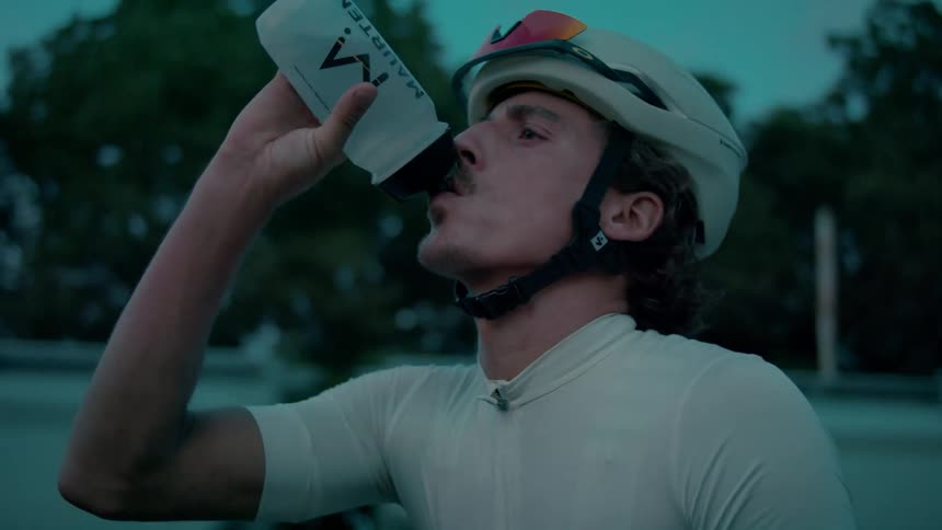 Portrait of a cyclist drinking water with a cargo train passing in the background